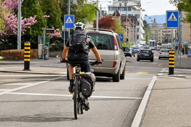 Basel, İsviçre - Nisan 2022: Şehir merkezinin eteklerindeki bir caddede işten eve bisikletle dönen kişi