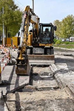 Basel, İsviçre - Nisan 2022: Mekanik kazıcı şehir merkezinin dışındaki bir yoldan eski pisti kapamak için kullanılıyor