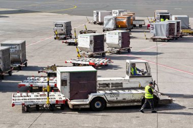 Frankfurt, Almanya - Nisan 2022: Arka planda daha fazla nakliye konteynırı bulunan bir havaalanına yüklemek için bir hava nakliye konteynırı toplayan araç