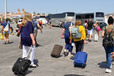 Aegina, Yunanistan, - Mayıs 2022: İnsanlar Aegina adasındaki limana bavullarını çekerek geliyorlar.