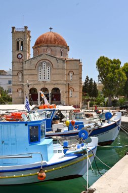 Aegina, Yunanistan, - Mayıs 2022: Arka planda Yunan Ortodoks Kilisesi Isodia Theotokou ile limanda demirlemiş küçük balıkçı tekneleri