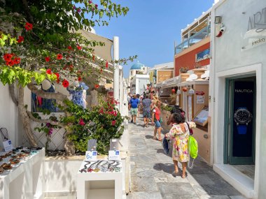 Oia, Santorini, Yunanistan - Haziran 2022: İnsanlar Oia kasabasının dar sokaklarında dükkanların önünden geçiyor.
