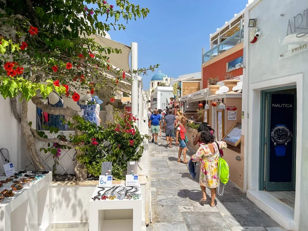 Oia, Santorini, Yunanistan - Haziran 2022: İnsanlar Oia kasabasının dar sokaklarında dükkanların önünden geçiyor.
