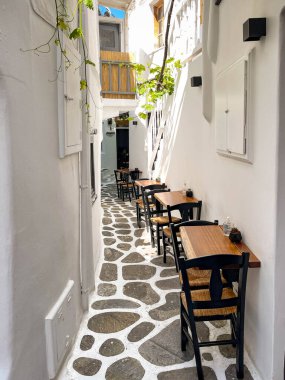 Mykonos, Yunanistan - Haziran 2022: Yunanistan 'ın Mykonos adasında dar bir sokakta bir restoranın küçük masaları