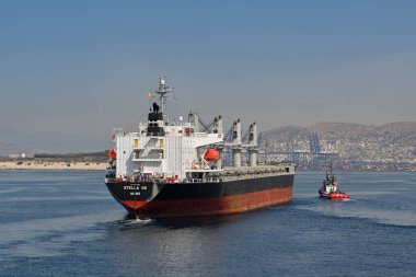 Pire, Atina, Yunanistan - Haziran 2022: Büyük kargo gemisi Stella GS bir römorkör teknesi tarafından Pire limanına götürülüyor.