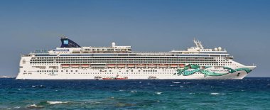 Mykonos, Yunanistan - Haziran 2022: Yunan Adası açıklarında denize demir atmış Norveç Yeşim yolcu gemisinin panoramik manzarası. Gemi NCL tarafından işletiliyor..