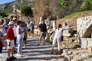 Efes, Kusadasi, Türkiye - Mayıs 2022: Ephesus 'taki antik Roma İmparatorluğu kentinin kalıntılarına gelen ziyaretçi partisine bir heykeli anlatan tur rehberi