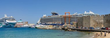 Rodos, Yunanistan - Mayıs 2022: Limanın yolcu gemileri ve feribotlarıyla panoramik manzarası. Sağda eski şehir duvarları var..
