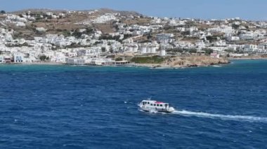 Mykonos, Yunan Adaları, Yunanistan, Haziran 2022: Dalgalı su ile Mykonos limanına doğru giden küçük bir tekne. Arka planda ünlü yel değirmenleri var..