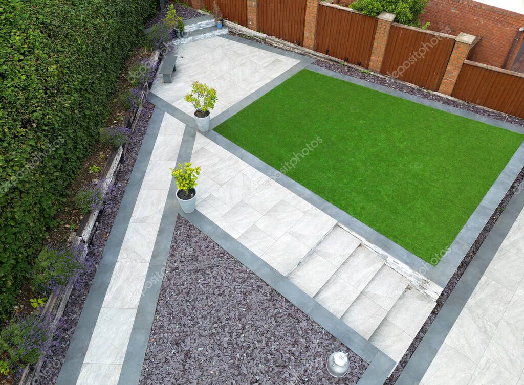 Aerial view of landscaped garden with contrasting light and dark grey porcelain tiles and artificial grass.. No people.
