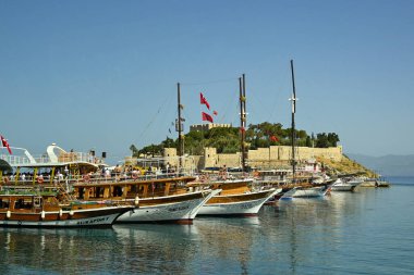 Kusadasi, Türkiye - Haziran 2022: Arka planda Güvercin Adası ile birlikte limanda demirlemiş turistik tekne sırası