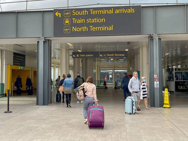 London, England - May 2022: Person pulling a suitcase walking into the entrance of London Gatwick airport