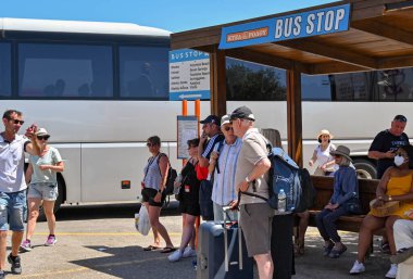 Lindos, Rhodes, Yunanistan - Mayıs 2022: Halk, kentin otobüs durağında bir kamu hizmeti otobüsü bekliyor