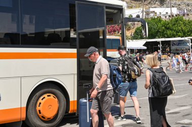 Lindos, Rhodes, Yunanistan - Mayıs 2022: Kentin otobüs durağında halk otobüsüne binen insanlar
