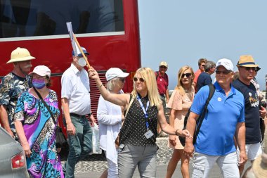Oia, Santorini, Yunanistan - Haziran 2022: Sanotini adasında bir turist grubuna rehberlik ediyor. Bazı insanlar maske takıyor..