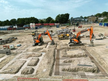 Pontypridd, Galler - Temmuz 2022: Güney Galler 'deki bir konut inşaatında yeni evler için üslerin yanına park etmiş mekanik kazıcıların havadan görünüşü.