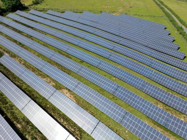 Aerial view of rows of solar panels instaked in a farm field. No people.