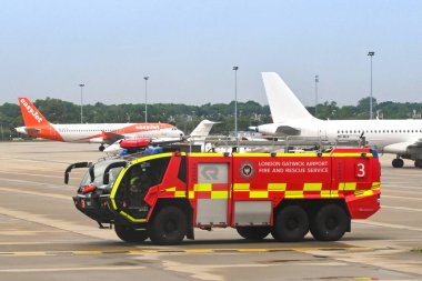 London, England - June 2022: Airport fire tender driving across the airport with planes in the background