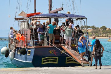 Aegina, Yunanistan - Mayıs 2022: İnsanlar adanın etrafındaki bir geziden sonra turistik gezi teknesinden iniyorlar