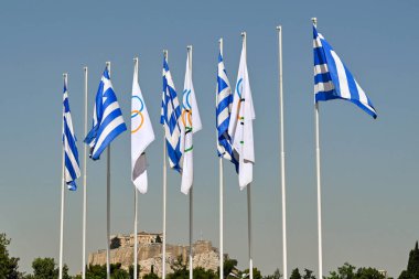 Atina, Yunanistan - Mayıs 2022: Yunan ulusal bayrakları kentin tarihi Olimpiyat Stadyumu 'nda dalgalanırken, arka planda Akroplis görülüyor