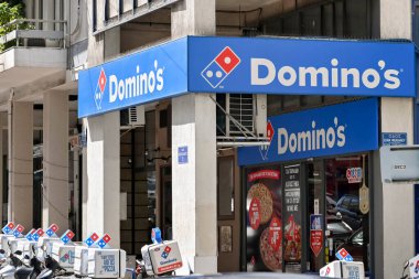 Athens, Greece - May 2022: Front of a branch of Domino's Pizzes in the city centre, with delivery bikes in front of the shop.