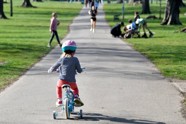 Cardiff, Wales - march 2022: Young child riding a small bicycle with stablisers through a public park