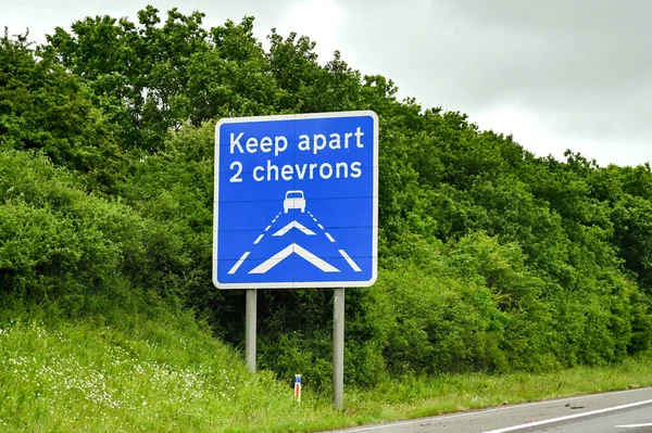 Road safety sign on a motorway asking drivers to maintain a safe distance behind the vehicles in front. No people.