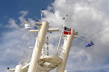 Athens, Greece - may 2022: Flags of Greece and the cruise ship operator Norwegian cruise Line flying from the mast on a ship