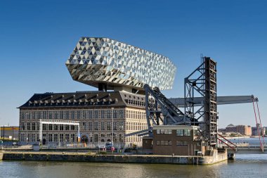 Antwerp, Belgium - August 2022: Exterior of the Antwerp Port Authority building in the city's commercial docks next to a lifting bridge with road deck raised. The architect was Zaha Hadid.