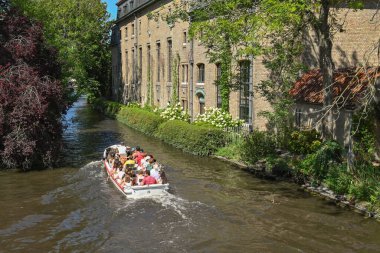 Bruges, Belgium - August 2022: Group of tourists in a motorboat being taken around the city's canal system