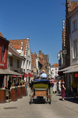 Bruges, Belgium - August 2022: Horse and cart taking visitors along one of the city's narrow streets