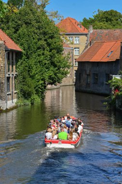 Bruges, Belgium - August 2022: Group of tourists in a motorboat being taken around the city's canal system