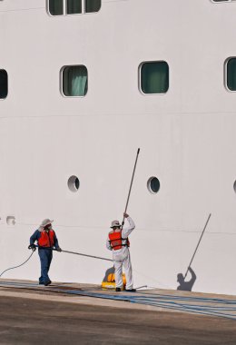 Rhodes, Greece - May 2022: Crew of a cruise liner cleaning the side of the ship while in port