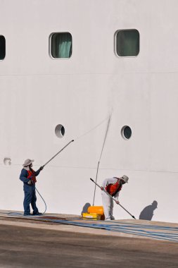 Rhodes, Greece - May 2022: Crew of a cruise liner cleaning the side of the ship while in port