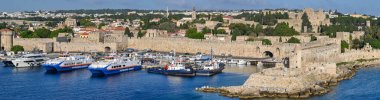 Rhodes, Greece - May 2022: Panoramic view of ferries moored in the harbour and the town's old walls