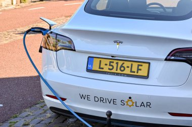 Utrecht, Netherlands - August 2022: Cable plugged in to recharge a Tesla electric car