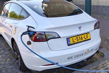 Utrecht, Netherlands - August 2022: Cable plugged in to recharge a Tesla electric car