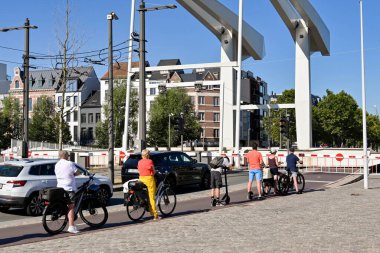 Antwerp, Belgium - August 2022: Cyclists and cars waiting for a lifting bridge to reopen on a road near one of the city's harbours