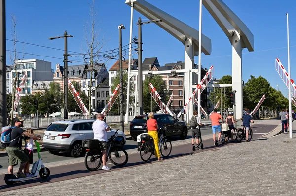 Antwerp, Belgium - August 2022: Cyclists and cars waiting as the gates of a lifting bridge are raised at one of the city's harbours