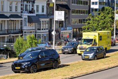 Rotterdam, Netherlands - August 2022: Cars mounting the grass verge on a city centre road to make room for an emergency ambulance to pass