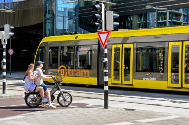Utrecht, Netherlands - August 2022: Two people on an electric bike waiting for a tram to pass