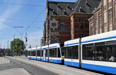 Amsterdam, Netherlands - August 2022: Electric tram arriving at a tram stop outside  the city's Centraale railway station
