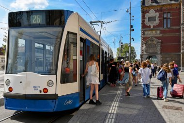 Amsterdam, Netherlands - August 2022: People getting off a modren electric tram at a tram stop outside  the city's Centraale railway station