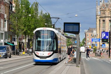 Amsterdam, Netherlands - August 2022: Modern electric tram arriving at at a tram stop in the city centre