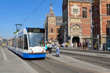 Amsterdam, Netherlands - August 2022: People getting off a modren electric tram at a tram stop outside  the city's Centraale railway station