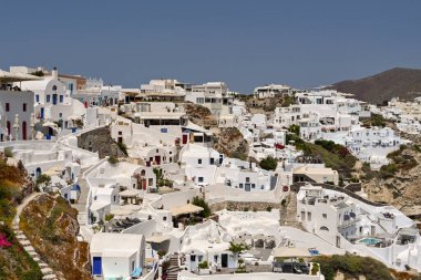 Oia, Santorini, Greece - June 2022: Traditional whitewashed buildings with terraces and baclonies overlooking the sea in Oia