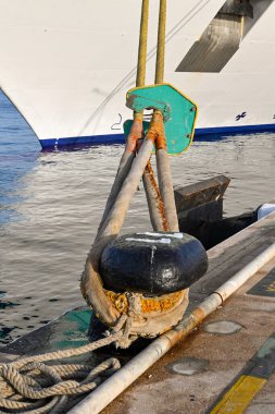 Close up view of mooring lines of a cruise ship looped around a mooring point in a commercial dock. No people.