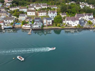 St Dogmael's, Pembrokeshire, Wales - August 2022: Aerial view of a small motorised dinghy sailing past the Ferry Inn pub and houses on the waterfront of the village at high tide.