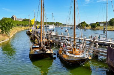Veere, Netherlands - August 2022: People on traditional wooden sailing boats moored near the town