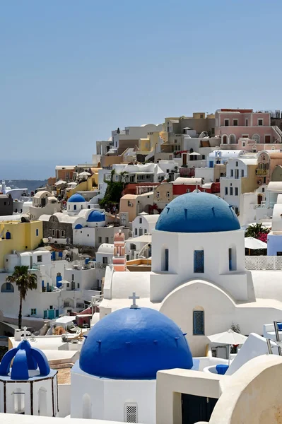 Oia, Santorini, Greece - June 2022: Traditional whitewashed buildings with blue domes overlooking the sea in Oia